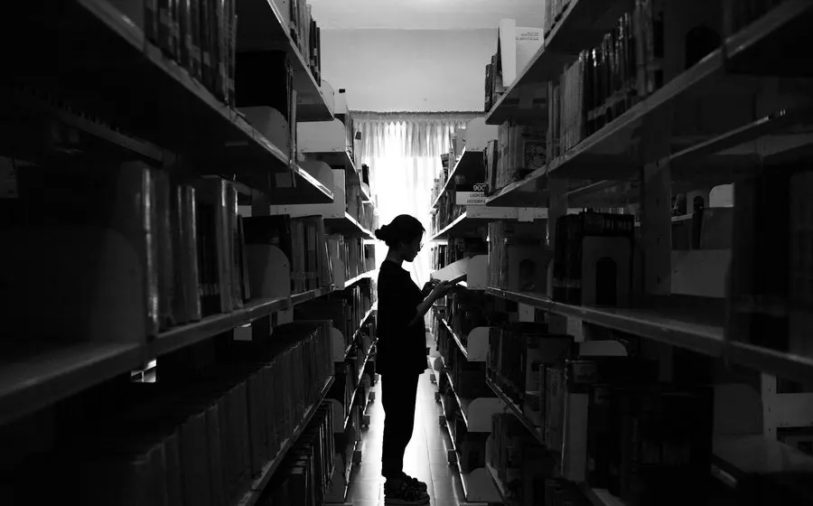A person in backlight between library shelves