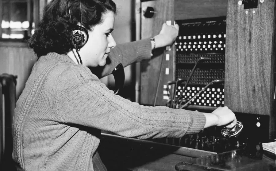 A telephone operator with a headset at a switchboard